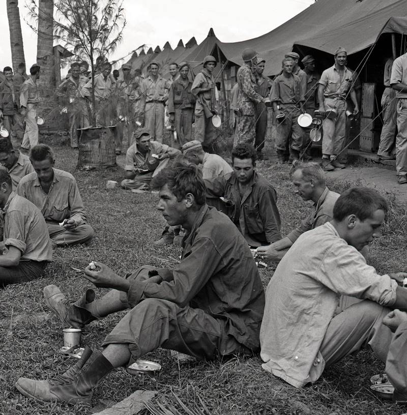 U.S. soldiers eat Christmas meals while other soldiers wait in line. The Philippines World War II